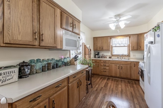 kitchen featuring white appliances, a sink, brown cabinets, and ceiling fan