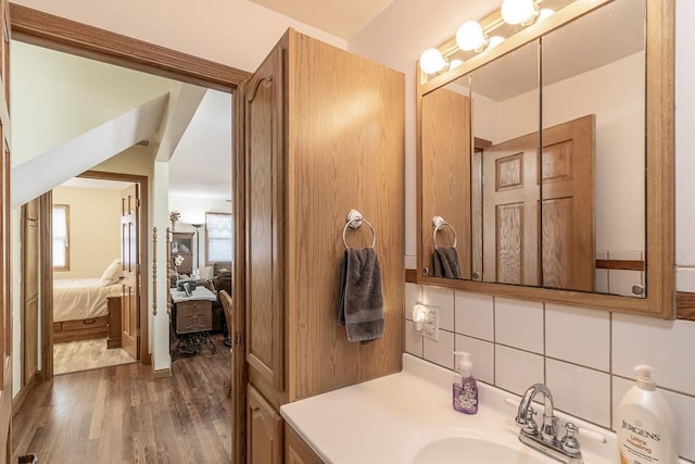 ensuite bathroom featuring vanity, decorative backsplash, wood finished floors, and ensuite bathroom