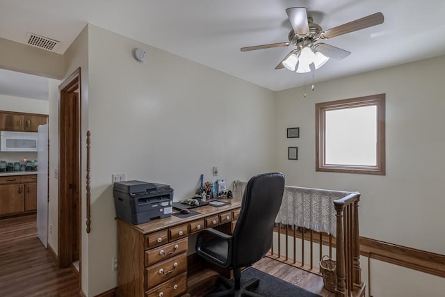 home office with visible vents, dark wood-style floors, and ceiling fan