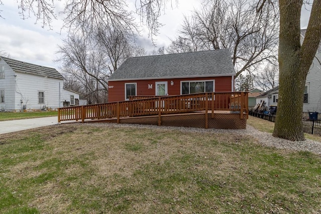 exterior space with a wooden deck, a yard, roof with shingles, and fence