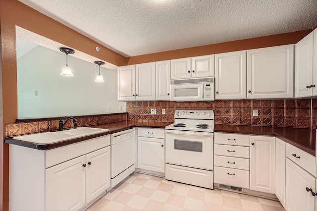 kitchen with white appliances, a sink, dark countertops, a textured ceiling, and white cabinets