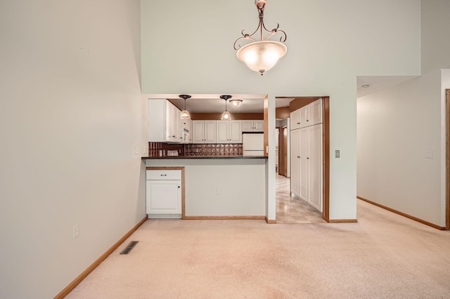 kitchen with white refrigerator, dark countertops, light carpet, and baseboards