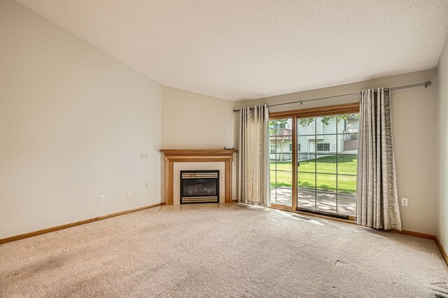 unfurnished living room with carpet floors, a fireplace, baseboards, and a textured ceiling