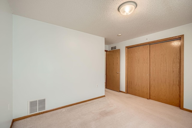 unfurnished bedroom with a closet, carpet floors, a textured ceiling, and baseboards