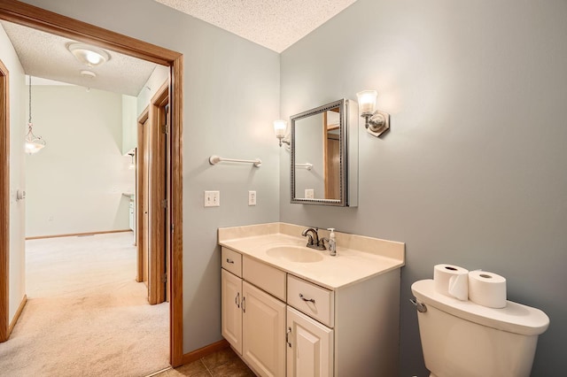 half bathroom featuring a textured ceiling, vanity, toilet, and baseboards