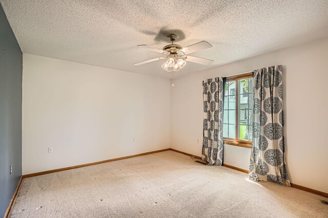 carpeted empty room with ceiling fan, baseboards, and a textured ceiling