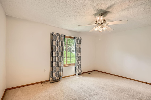 unfurnished room with carpet floors, a ceiling fan, a textured ceiling, and baseboards
