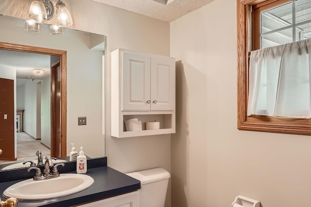 bathroom featuring toilet, vanity, and a textured ceiling