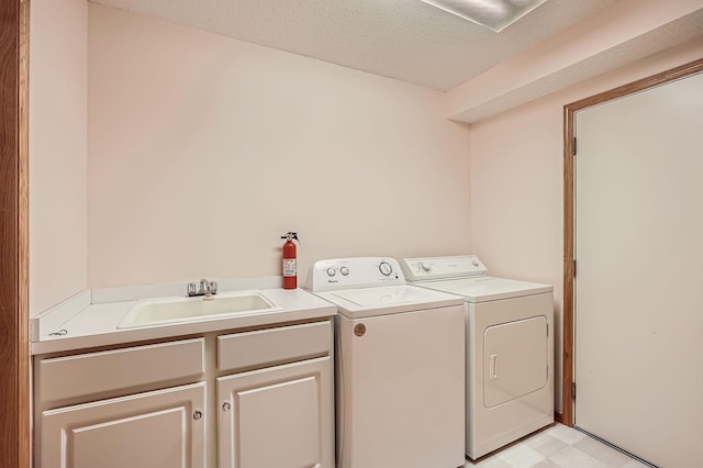 laundry area featuring washing machine and dryer, cabinet space, a textured ceiling, and light floors
