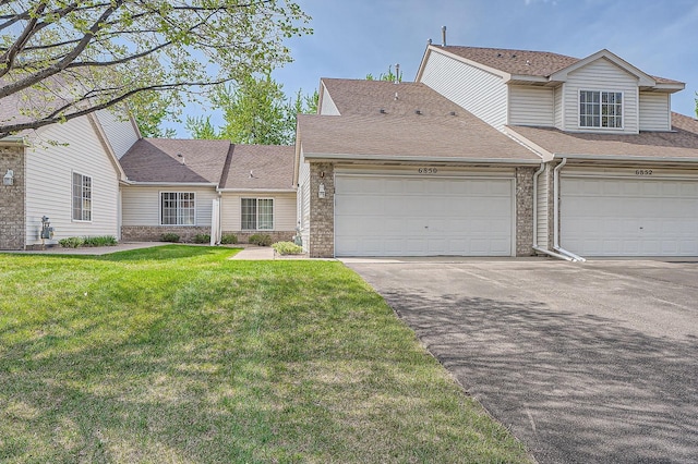 view of front of home with brick siding, a front lawn, driveway, and roof with shingles