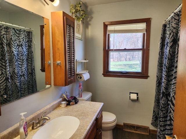 bathroom with toilet, baseboards, visible vents, wood finished floors, and vanity