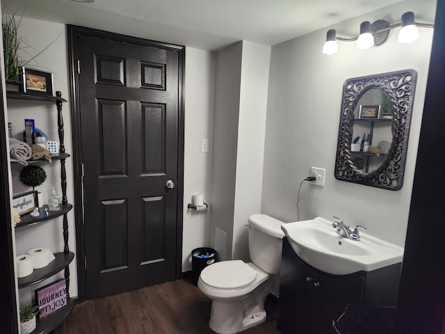 half bathroom with toilet, vanity, and wood finished floors