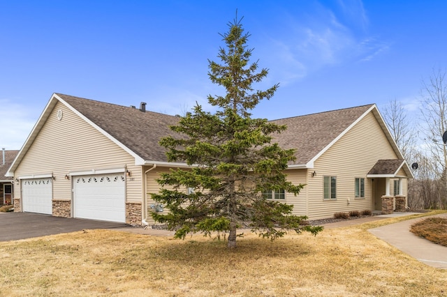 view of front of house featuring aphalt driveway, stone siding, a shingled roof, and a garage