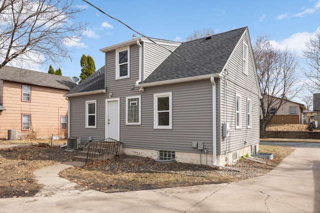 rear view of property featuring cooling unit and a shingled roof