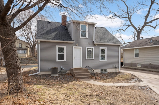 rear view of house with a shingled roof, a chimney, and central AC