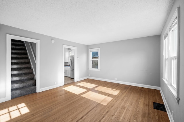 3806 Jackson St NE, Columbia Heights, MN 55421 - unfurnished living room with a textured ceiling, baseboards, wood finished floors, and stairs