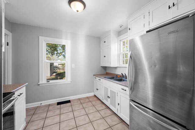 3806 Jackson St NE, Columbia Heights, MN 55421 - kitchen with freestanding refrigerator, a sink, baseboards, white cabinetry, and light countertops