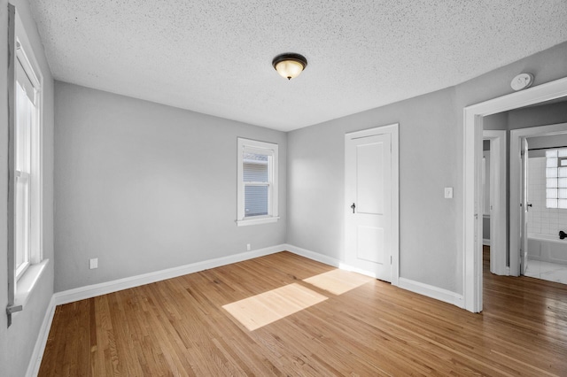 3806 Jackson St NE, Columbia Heights, MN 55421 - unfurnished bedroom with wood finished floors, baseboards, a textured ceiling, and multiple windows