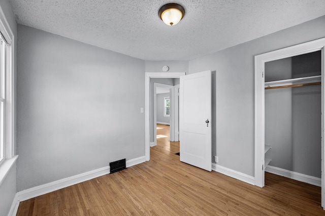 3806 Jackson St NE, Columbia Heights, MN 55421 - unfurnished bedroom featuring a closet, a textured ceiling, baseboards, and wood finished floors