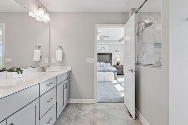 full bath with ensuite bath, a tile shower, ceiling fan, double vanity, and baseboards