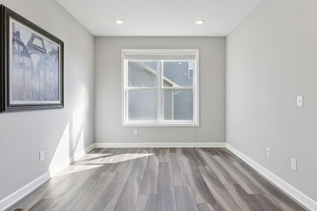 spare room with wood finished floors, baseboards, and recessed lighting