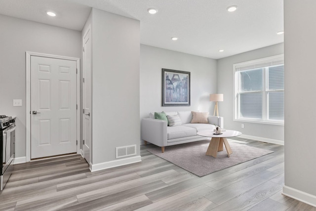 living room with light wood finished floors, baseboards, and recessed lighting