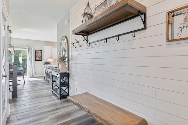 mudroom with wood finished floors and wood walls