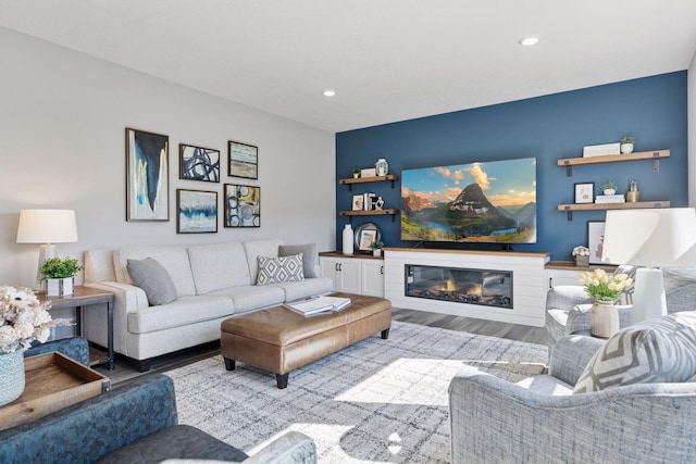 living room featuring wood finished floors, a glass covered fireplace, and recessed lighting