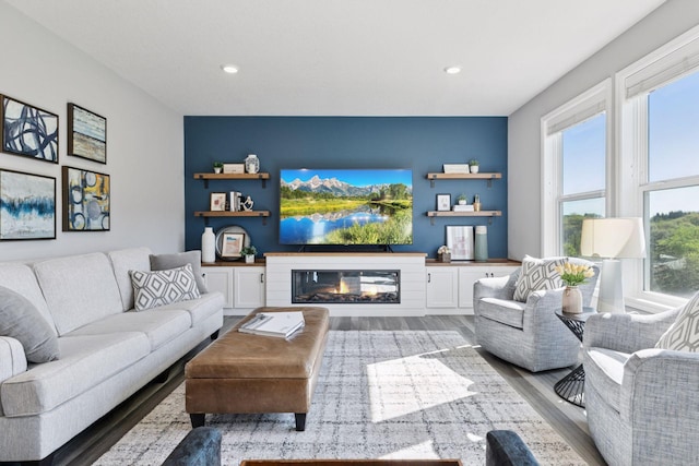 living area featuring wood finished floors, healthy amount of natural light, a glass covered fireplace, and recessed lighting