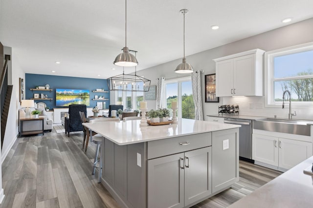kitchen with dishwasher, a sink, light countertops, white cabinetry, and wood finished floors