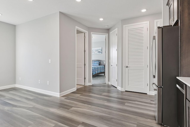 interior space featuring freestanding refrigerator, baseboards, light wood-style floors, light countertops, and dark brown cabinets