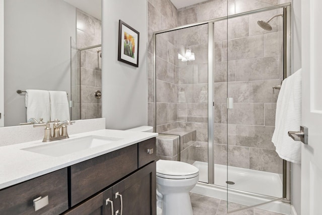 bathroom featuring a stall shower, vanity, toilet, and tile patterned flooring