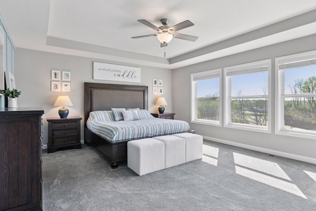carpeted bedroom featuring a tray ceiling, baseboards, and ceiling fan