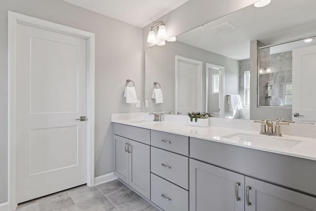 full bath with double vanity, a tile shower, and baseboards