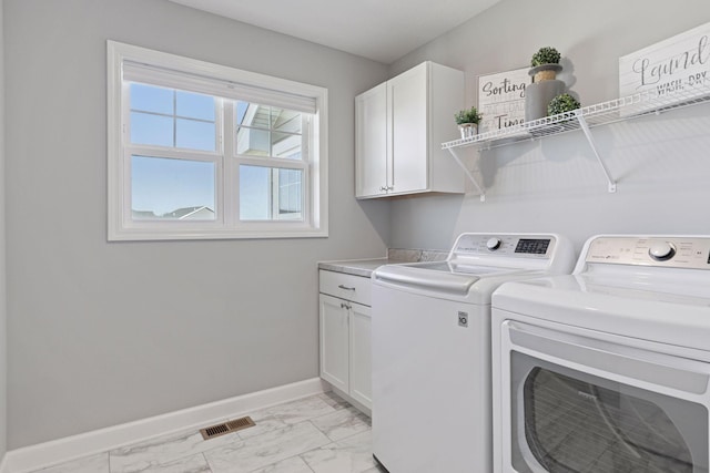 washroom with cabinet space, washing machine and clothes dryer, light marble finish flooring, and baseboards