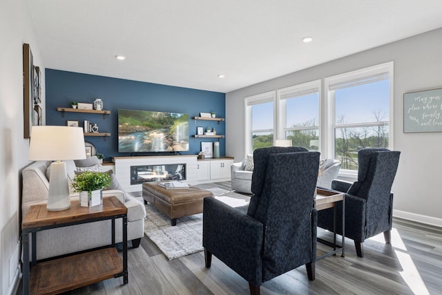living area featuring wood finished floors, recessed lighting, and a glass covered fireplace