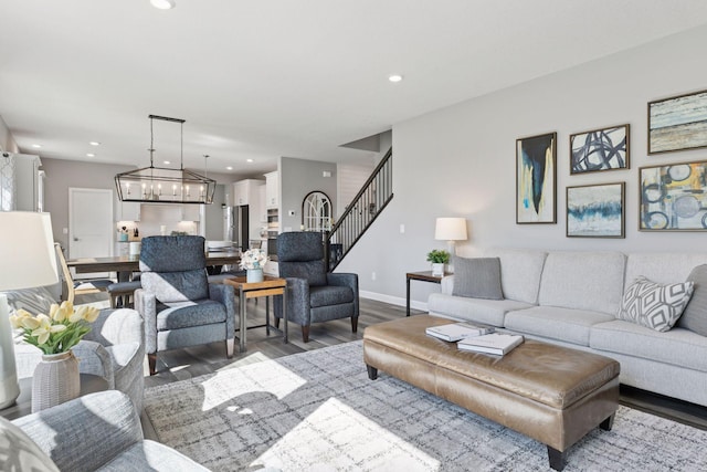 living room featuring wood finished floors, stairs, baseboards, recessed lighting, and a chandelier