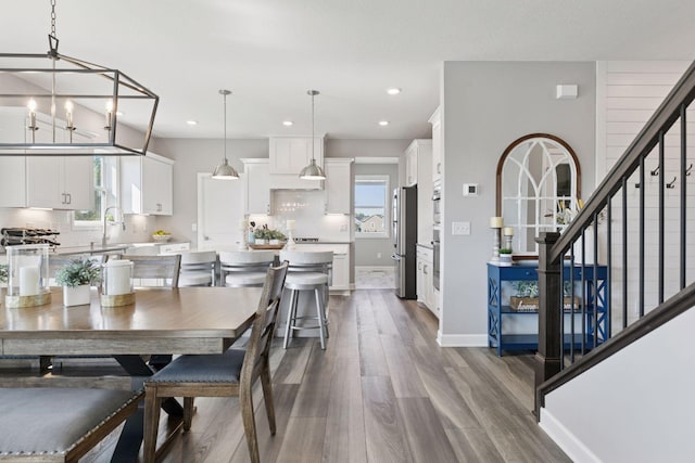 dining room featuring wood finished floors, stairs, recessed lighting, and baseboards