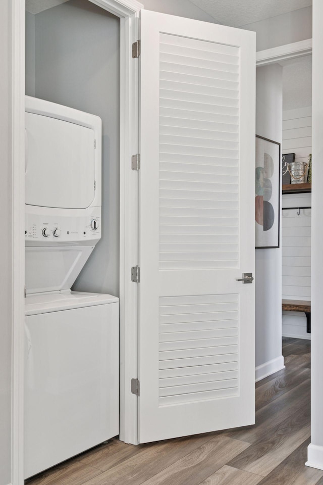washroom with estacked washer and dryer and wood finished floors