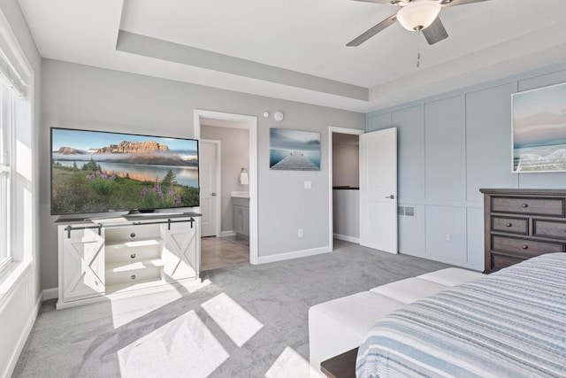 bedroom featuring light colored carpet, baseboards, and a tray ceiling