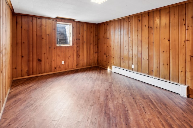 1331 8th Ave N, Saint Cloud, MN 56303 - unfurnished room featuring a baseboard radiator, wood finished floors, wooden walls, and baseboards