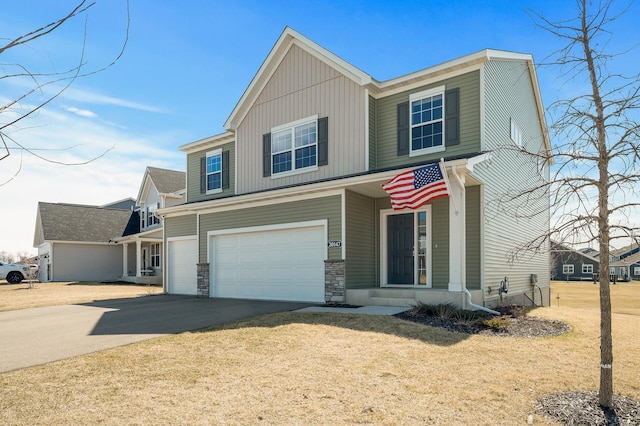 view of front of home featuring a front lawn, driveway, stone siding, an attached garage, and board and batten siding