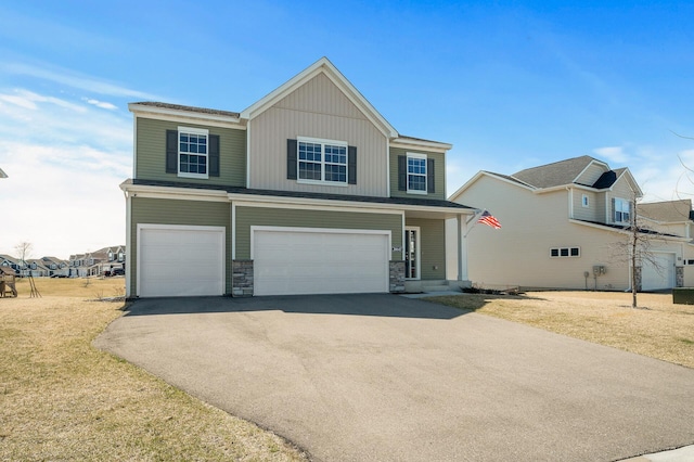 view of front of property with stone siding, a front lawn, aphalt driveway, and a garage