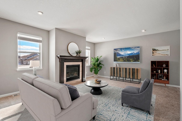 carpeted living area featuring baseboards, a glass covered fireplace, visible vents, and recessed lighting