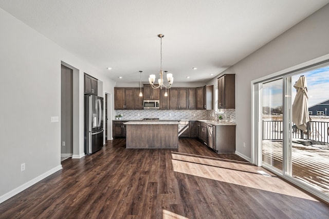 kitchen with dark brown cabinets, decorative backsplash, light countertops, appliances with stainless steel finishes, and a kitchen island