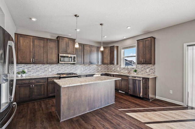 kitchen with stainless steel appliances, a sink, dark wood-style flooring, dark brown cabinets, and decorative backsplash