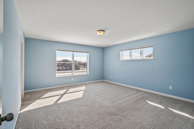 unfurnished room featuring a textured ceiling, carpet flooring, and baseboards
