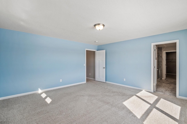 unfurnished bedroom with a walk in closet, carpet flooring, and baseboards