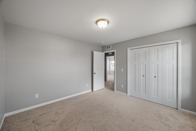 unfurnished bedroom featuring visible vents, baseboards, carpet flooring, and a closet