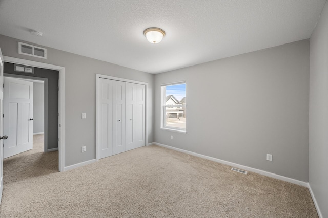 unfurnished bedroom with baseboards, carpet floors, visible vents, and a closet